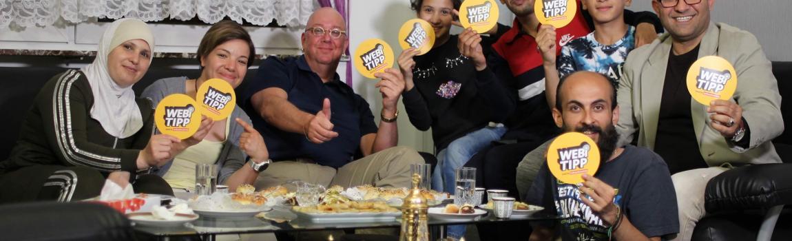 Verbraucherzentrale Saarland Geflüchtete halten Kärtchen hoch mit Webi Tipp Verbrauchertipps