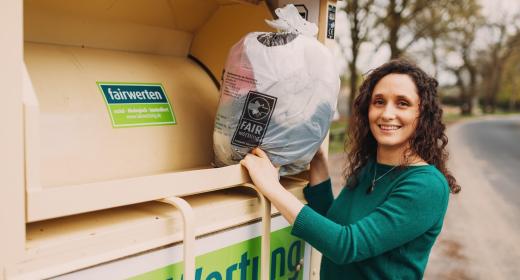 Frau vor Altkleidercontainer von FairWertung